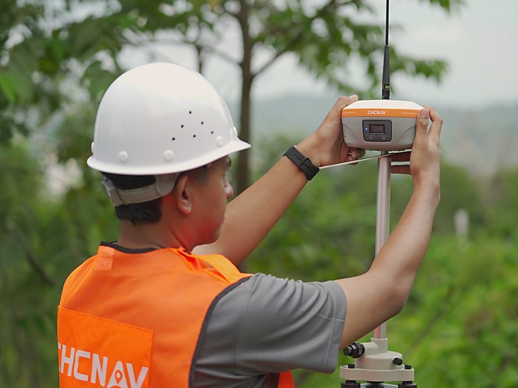 Géomètre utilisant le récepteur GNSS CHCNAV i85 sur le terrain pour l'arpentage.
