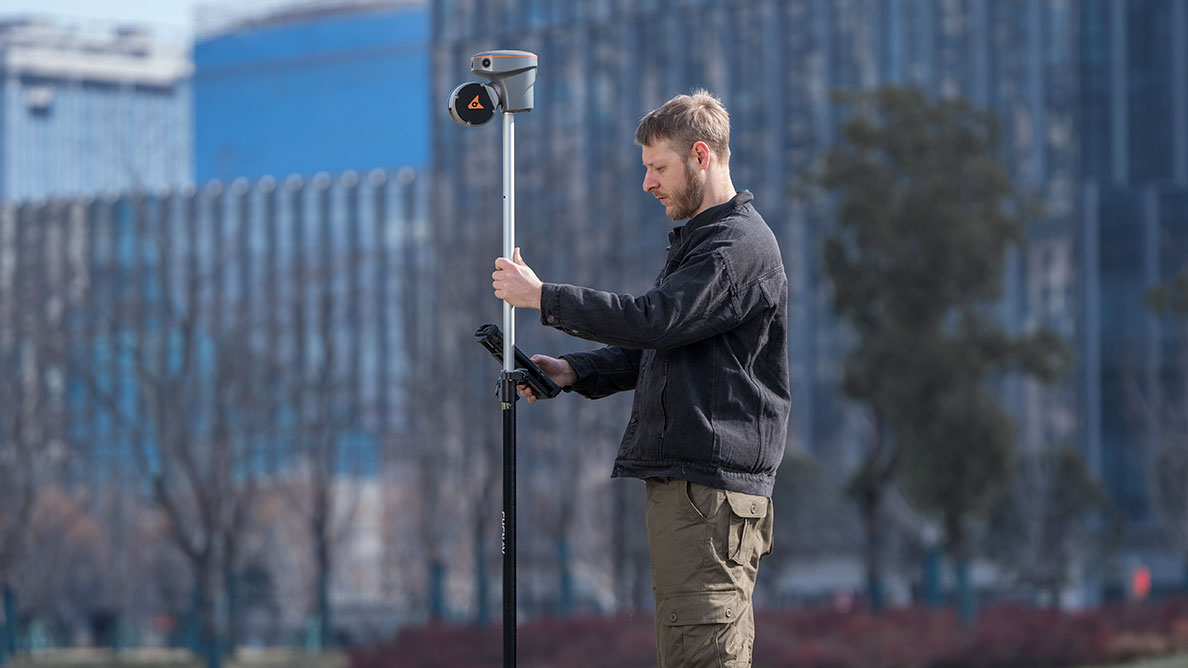 A surveyor using the CHCNAV RS10 GNSS receiver mounted on a tripod for accurate positioning in an urban setting.