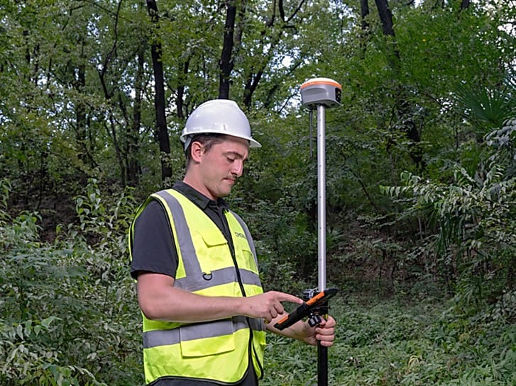 Géomètre utilisant le récepteur GNSS CHCNAV i85 sur le terrain pour l'arpentage.