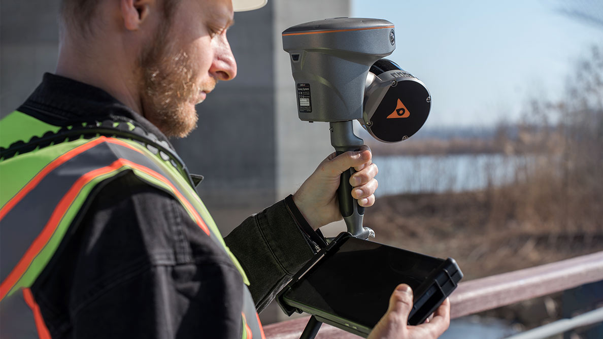 A user setting up the CHCNAV RS10 GNSS receiver with a tablet in the field for precise surveying and mapping.
