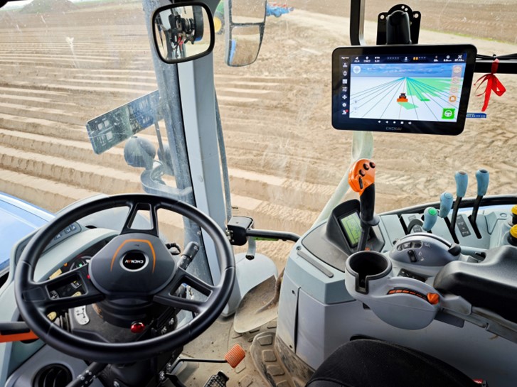 Ecrã de auto-direção CHCNAV no interior da cabina de um trator.